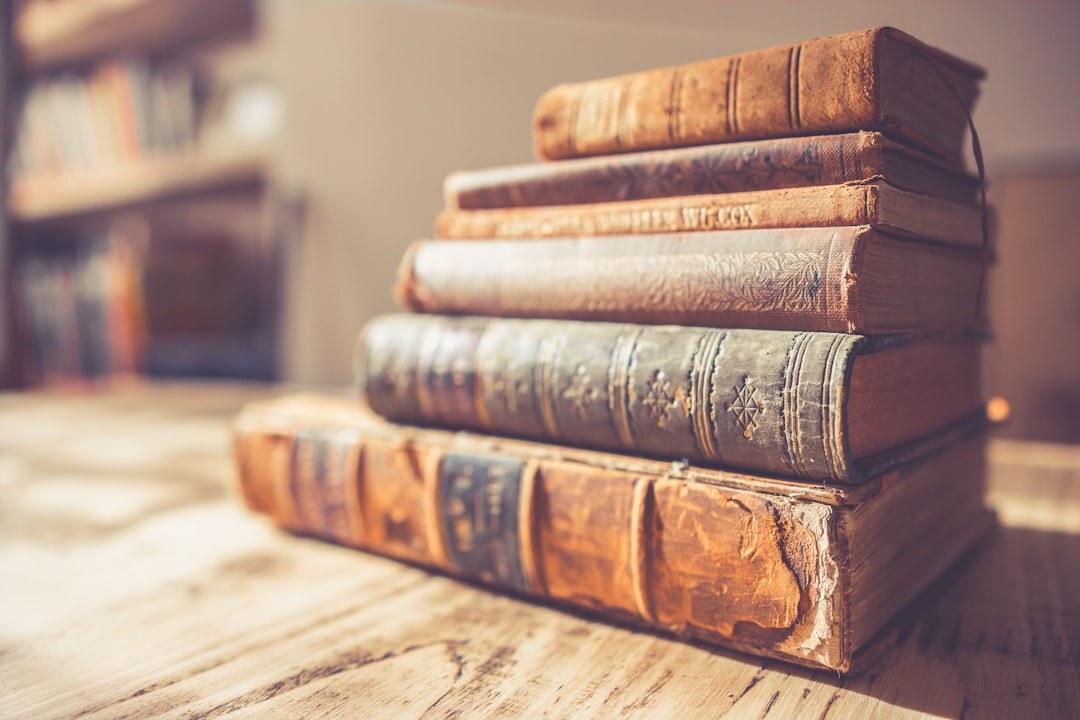 Stack of old worn hardcover books lit by warm side light