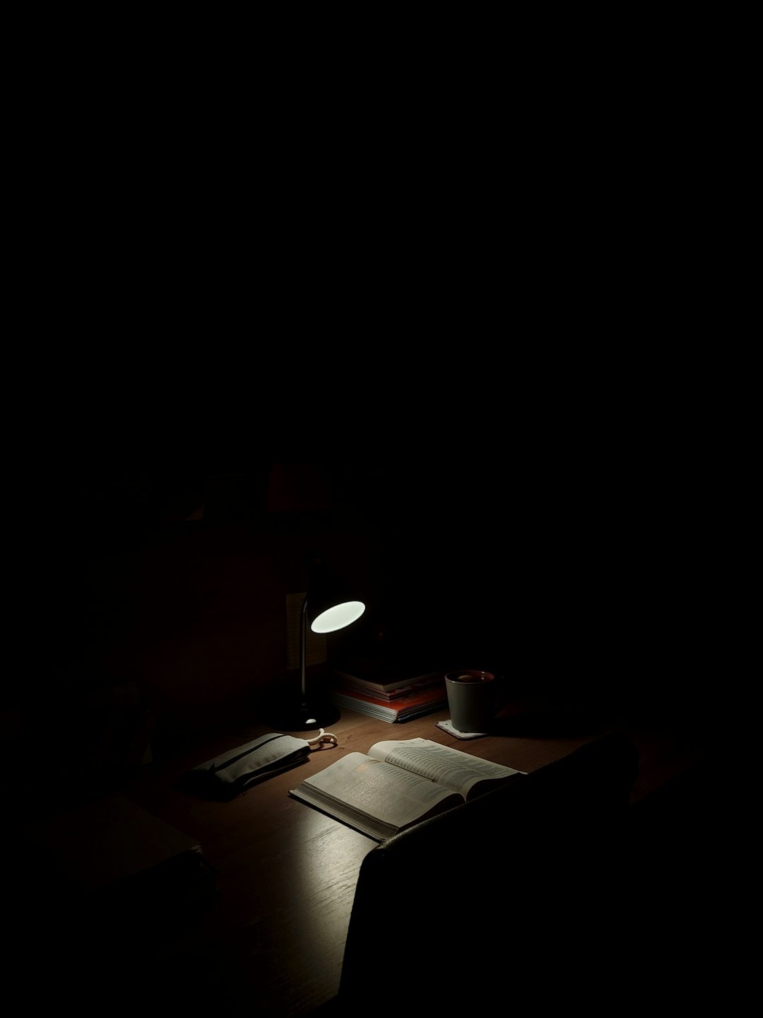 Detective desk with a lit lamp, notebook and magnifying glass at night