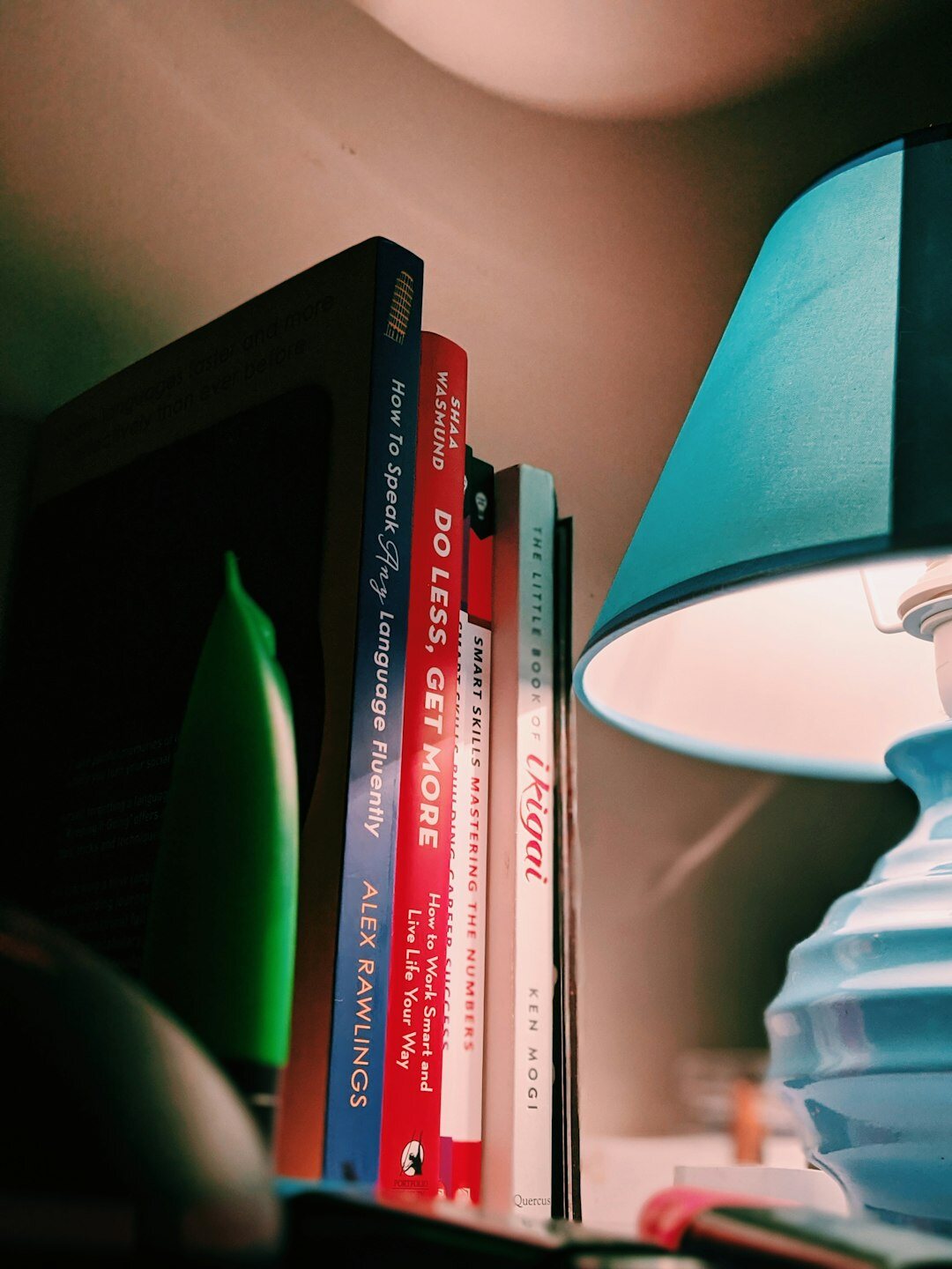 Stack of hardcover books next to a warm reading lamp